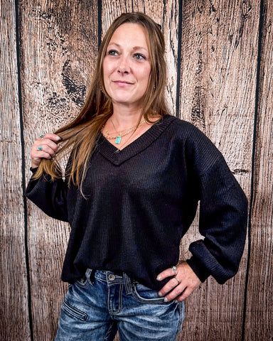The Hadley Top in black styled and modeled on women in front of wood background.