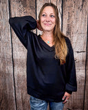 The Hadley Top in black styled and modeled on women in front of wood background.