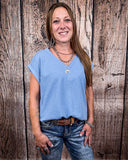The Sloan Top in denim blue being styled with jeans and worn on women in front of wood background.