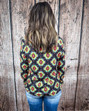 The Palmer Pullover being styled with jeans and worn by a women in front of wood background.