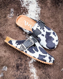 Andi Slip on Mule in Black Cow Print by Very G displayed on cowhide.