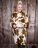 Cow Print Hooded Blanket being worn by a women in front of wood background.