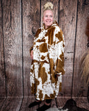 Cow Print Hooded Blanket being worn by a women in front of wood background.