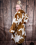 Cow Print Hooded Blanket being worn by a women in front of wood background.