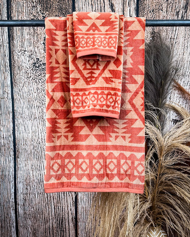 Navajo Adobe Towels displayed on rod in front of wood background.