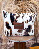 Wrangler Tri-Color Cowhide Travel Blanket displayed on wood table in front of wheat background.