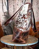 Side view of the Westin Hair on Hide Tote Bag on a wooden table with wheat in the background.