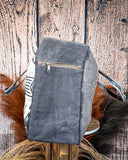 Side view of the Black Sands Weekender Bag on a wooden table with wheat in the background.