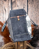 Side view of the Black Sands Weekender Bag on a wooden table with wheat in the background.