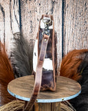Side view of the The Salt Creek Hair on Hide Crossbody Bag displayed on a wooden table.