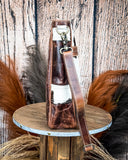 Side view of the The Salt Creek Hair on Hide Crossbody Bag displayed on a wooden table.