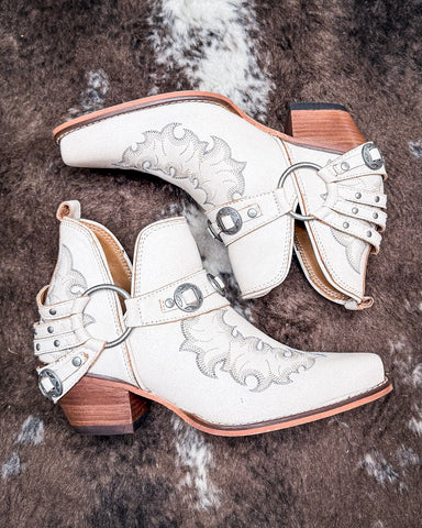 The Western Ember Booties in White displayed on cowhide.
