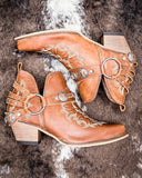 The Western Ember Booties in Canyon Brown displayed on cowhide.