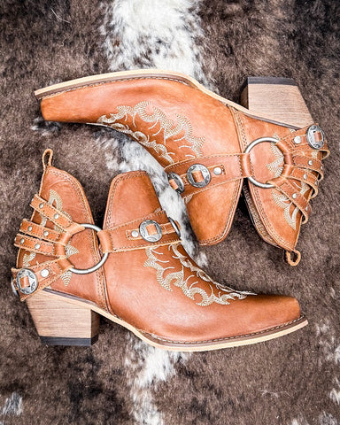 The Western Ember Booties in Canyon Brown displayed on cowhide.
