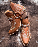 Front and side view of the  Western Ember Booties in Canyon Brown displayed on cowhide.