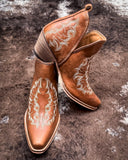 Front and side view of the Western Ember Booties in Canyon Brown displayed on cowhide.