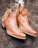Side view of the Western Ember Booties in Canyon Brown displayed on cowhide.