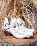 The Western Ember Booties in White displayed on a table with wheat in the back.