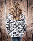 Back view of a model wearing the Life is a Rodeo Soft Shell Jacket with a wood backdrop.