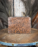 Back of the Wonder Trail Card Holder in Caramel on a wooden table with wheat in the back.