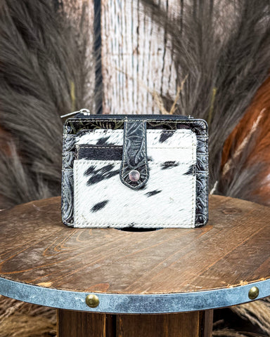 The Wonder Trail Card Holder in Black on a wooden table with wheat in the back,  wood backdrop.