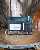 The back of the Pride of Prickly Pears Card Holder in Black on a wooden table with wheat in the back
