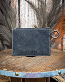 The back of the Wind Rider Card Holder in Chocolate Brown on a wooden table with wheat in the back.