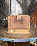 Inside of the Wind Rider Card Holder in Brown on a wooden table with wheat in the back.