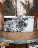 Black and white cowhide wallet on a wooden surface with a rustic background