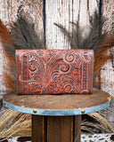Brown leather wallet with intricate patterns on a wooden surface with a rustic background