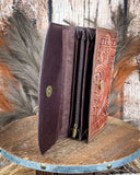 Brown leather wallet with intricate designs on a wooden surface
