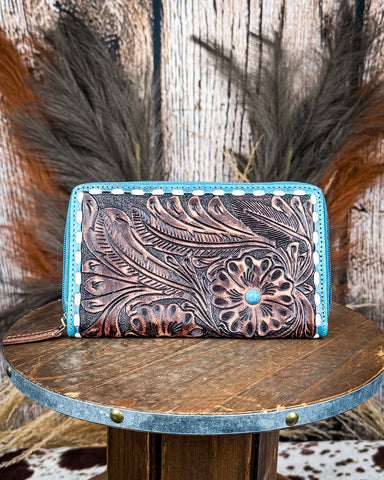 Handcrafted leather wallet with floral patterns on a wooden surface