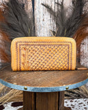 Handcrafted leather wallet with intricate patterns on a wooden surface.