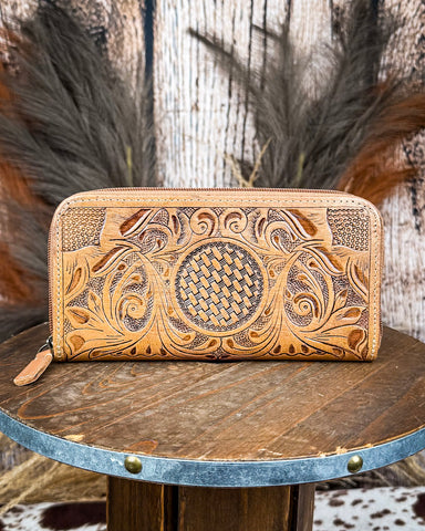 Handcrafted leather wallet with intricate patterns on a wooden surface