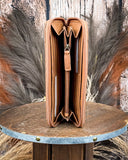 Brown leather wallet on a wooden stand with feathers in the background