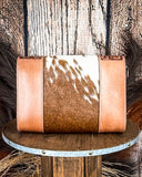 Handbag with cowhide pattern on a wooden surface with rustic background