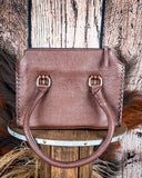 Brown leather handbag on a wooden block with a rustic background