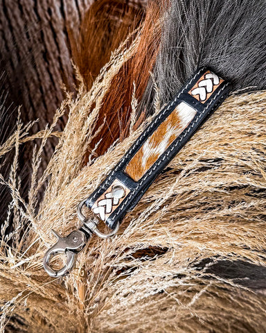 Close-up of a leather key fob with braided design on a textured background