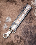 Leather strap with braided design and metal clasp on a textured brown background