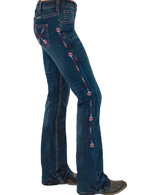 A side view of a person wearing dark blue western flare jeans with red and white embroidered floral details running down the outer leg, paired with brown boots against a white background.