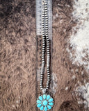 The Lola Flower Pendant Fashion Necklace on a ruler to show size. Cowhide background.
