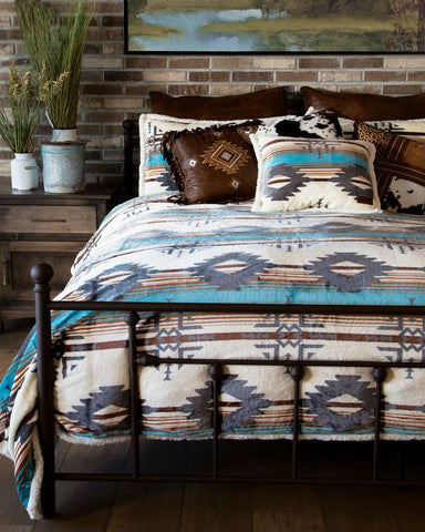 Bedroom with a bed featuring a patterned comforter, pillows, and a brick wall with a painting.