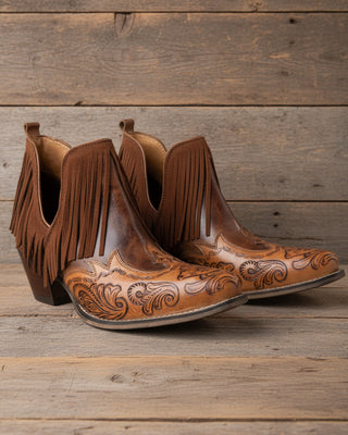 Pair of brown cowboy boots with fringes on a white background