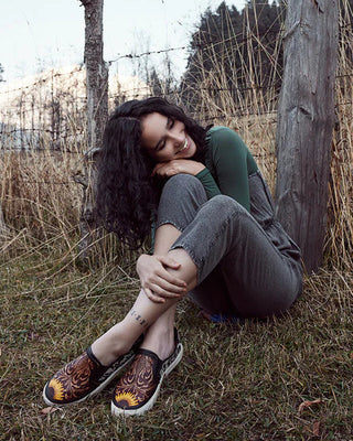 Woman sitting against a wooden post in a natural setting