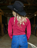 Back view of a cowgirl wearing the Garnet Grit Pullover Button Up inside of a barn.