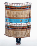 The Cactus Stripe Travel Blanket rolled out to show the pattern held by a person in a white backdrop
