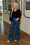 Woman in black sweater and blue jeans standing in an art gallery.