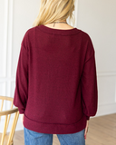 The Hadley Top in wine being styled with jeans and worn by a women in studio setting.