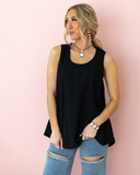 The Caldera Tank in Black being styled and modeled by a women in front of blank pink background.
