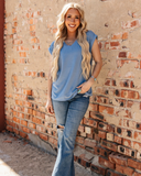 The Sloan Top in denim blue being styled and modeled on women in front of brick wall.